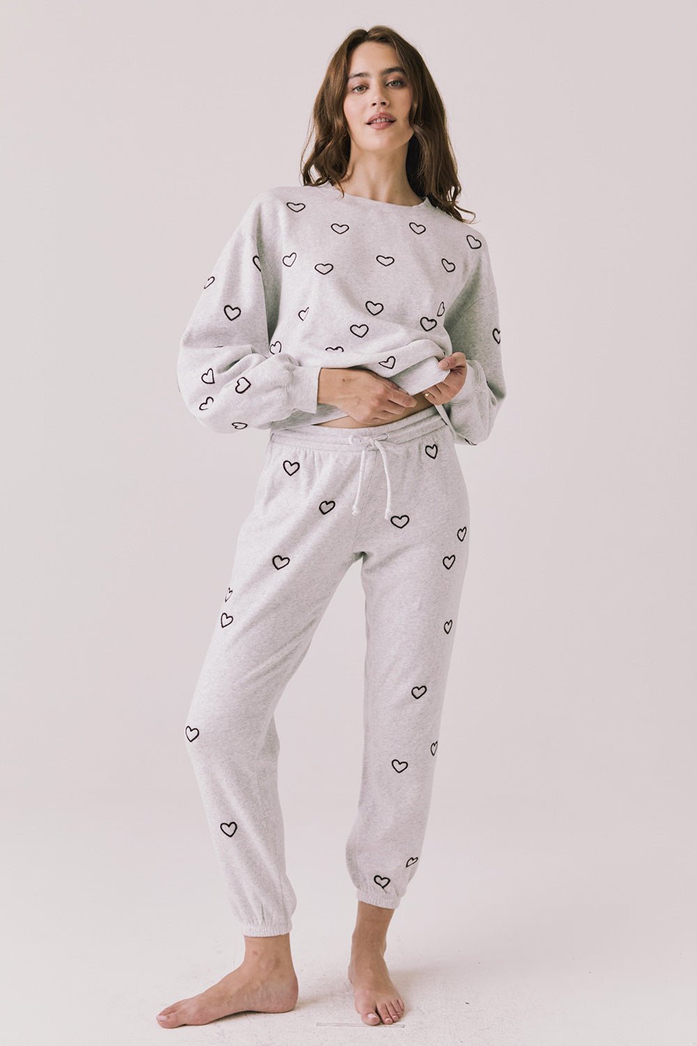 Woman wearing a light gray pajama sweathirt with heart print