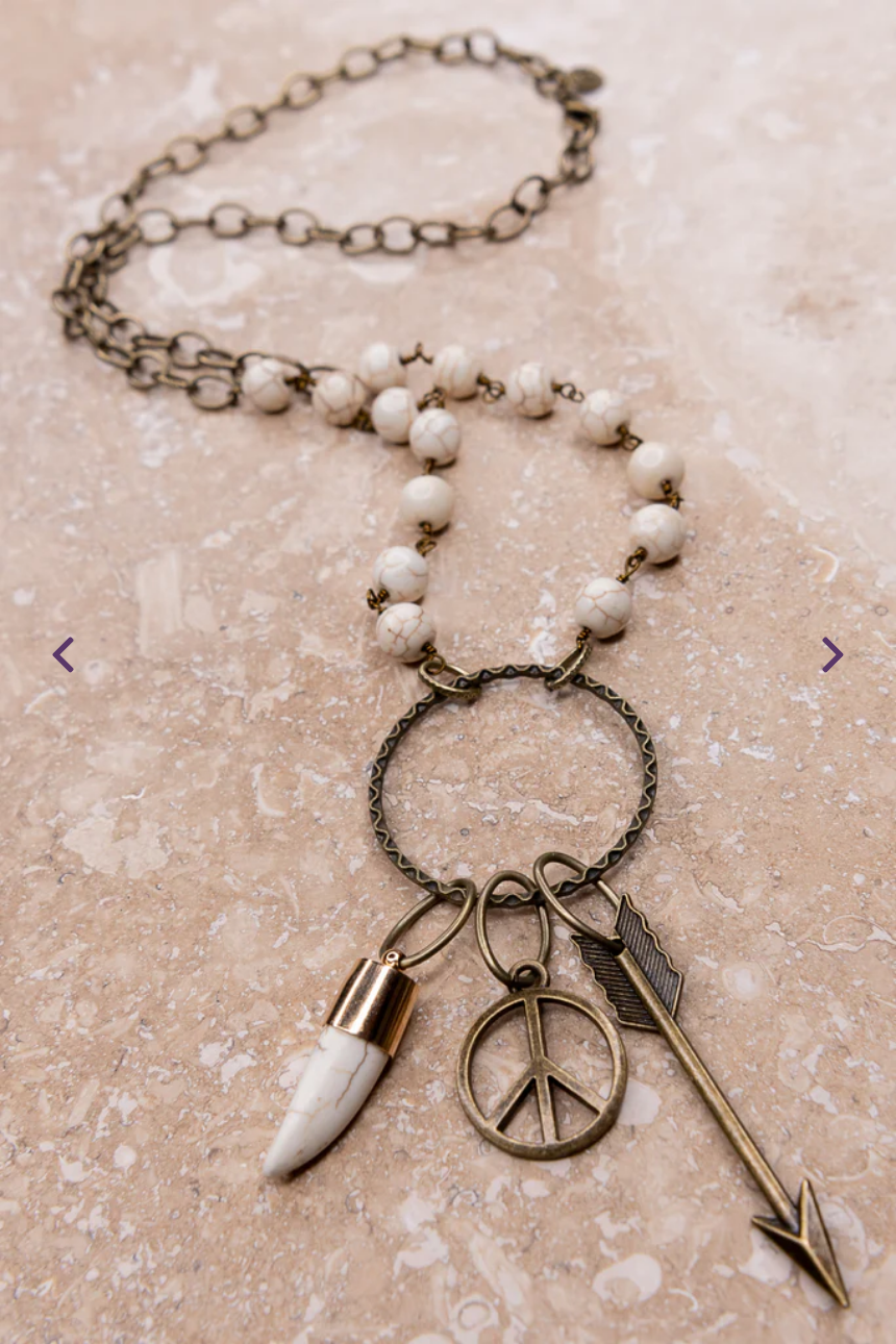 Necklace with peace sign, arrow, and other charms on a beige background