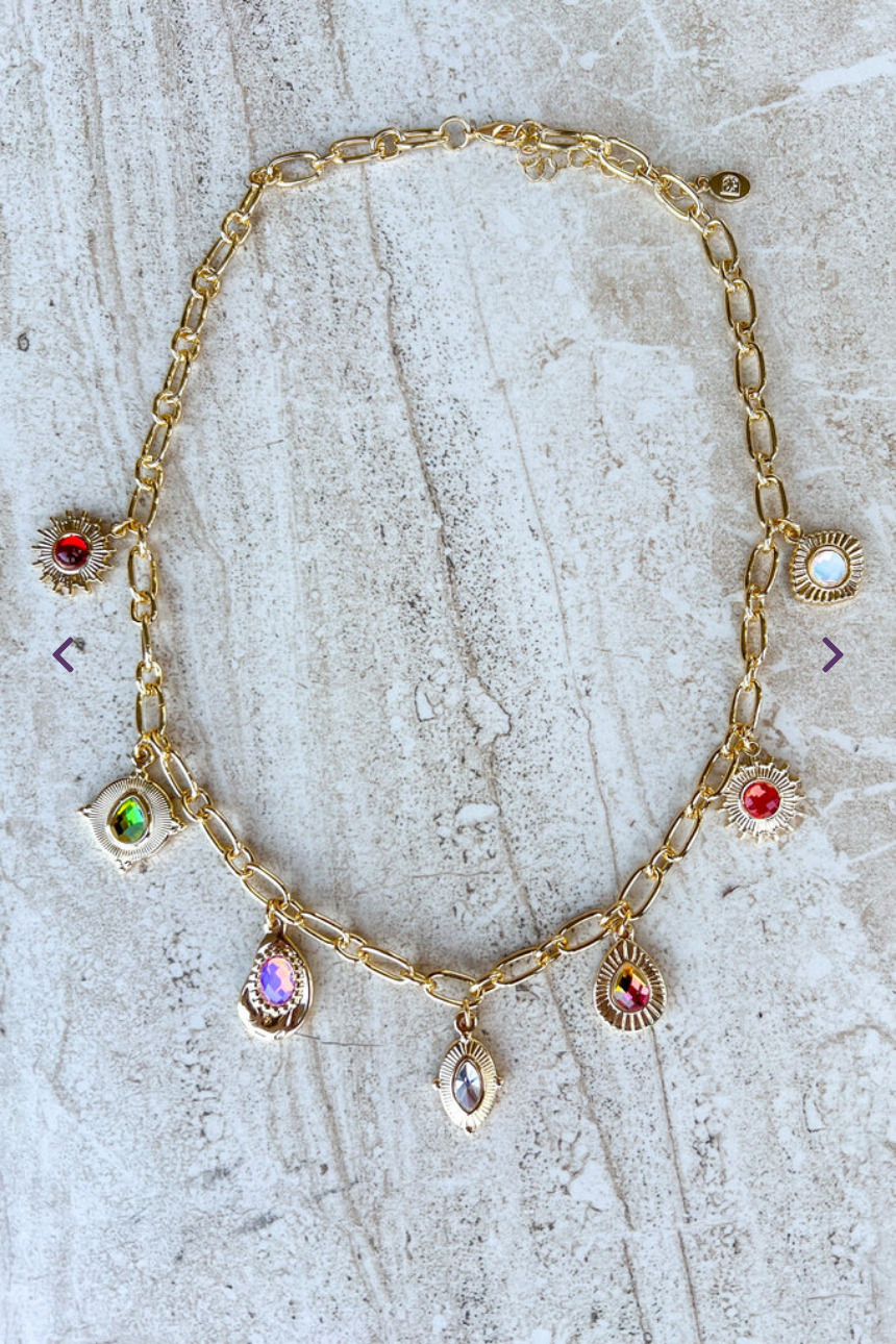 Gold necklace with gemstone pendants on a textured surface