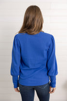 Mac modeling the back of the gathered shoulder top in blue