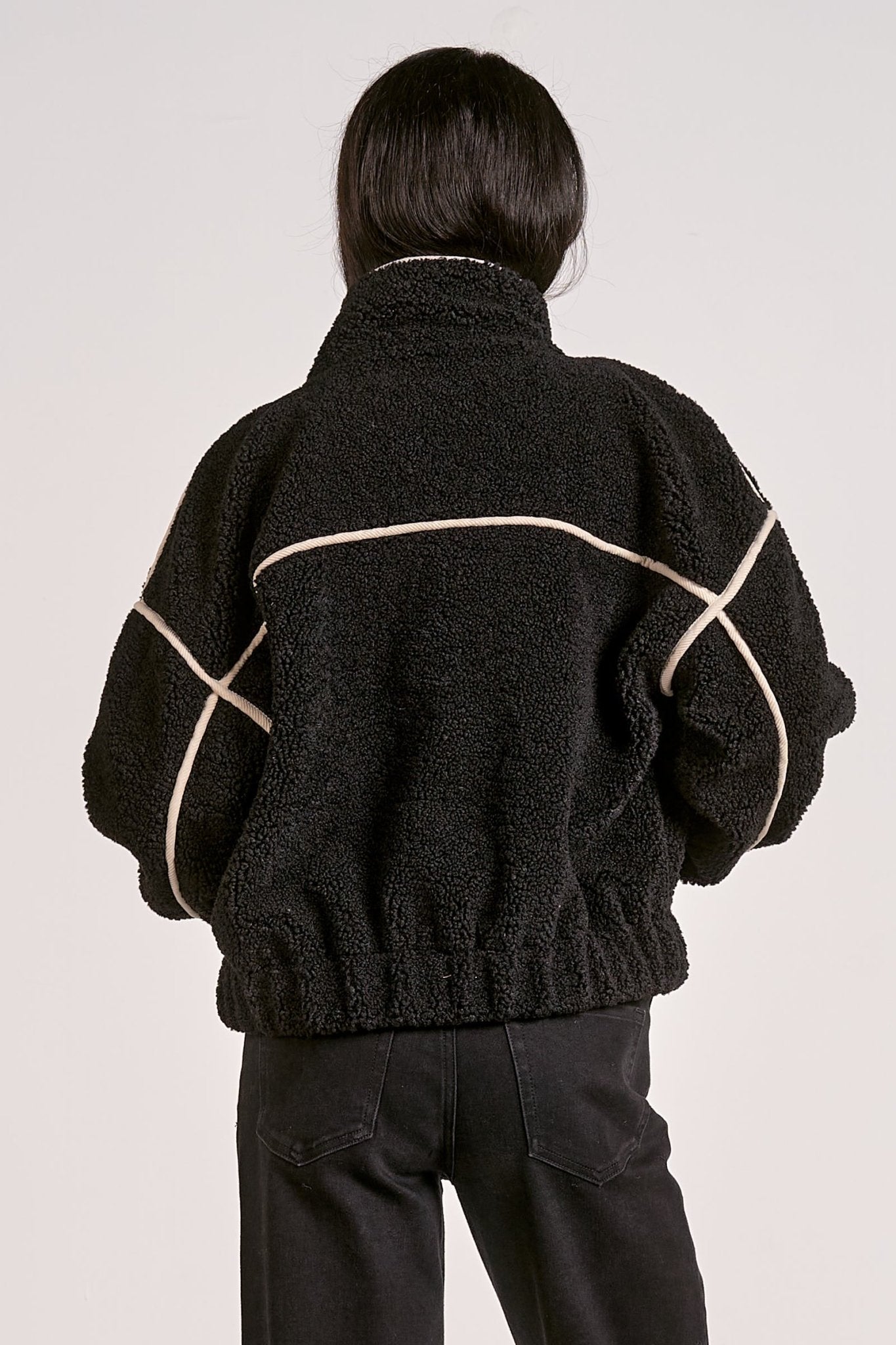 woman showing the back of the  black sherpa bomber jacket with contrast trim 