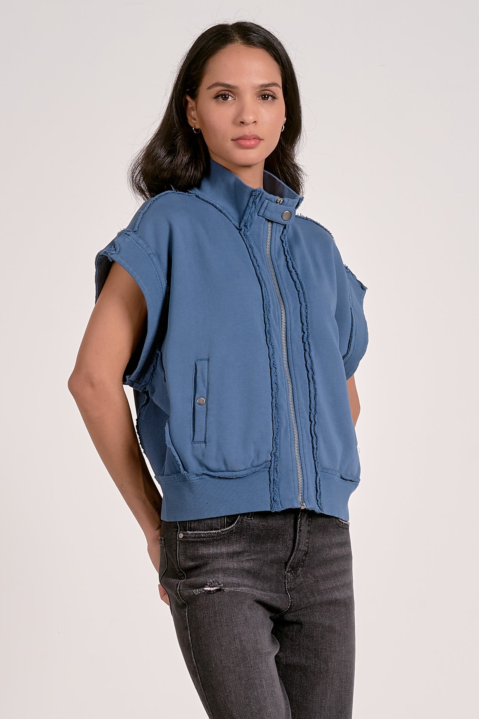 Woman wearing a blue sleeveless jacket on a white background